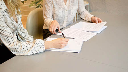 Two women sitting next to each other going over paperwork.