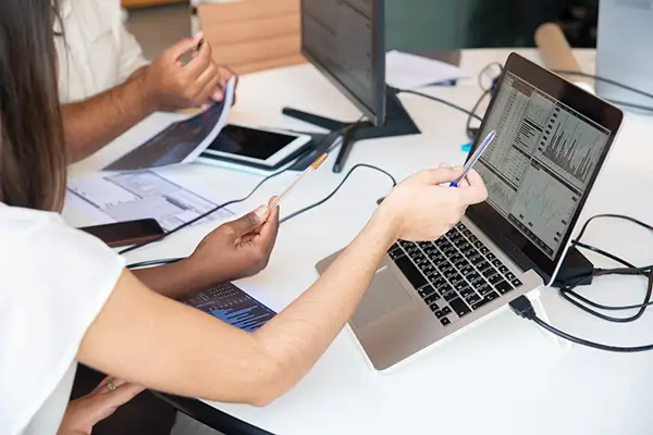 Hands Pointing to a Laptop comparing data